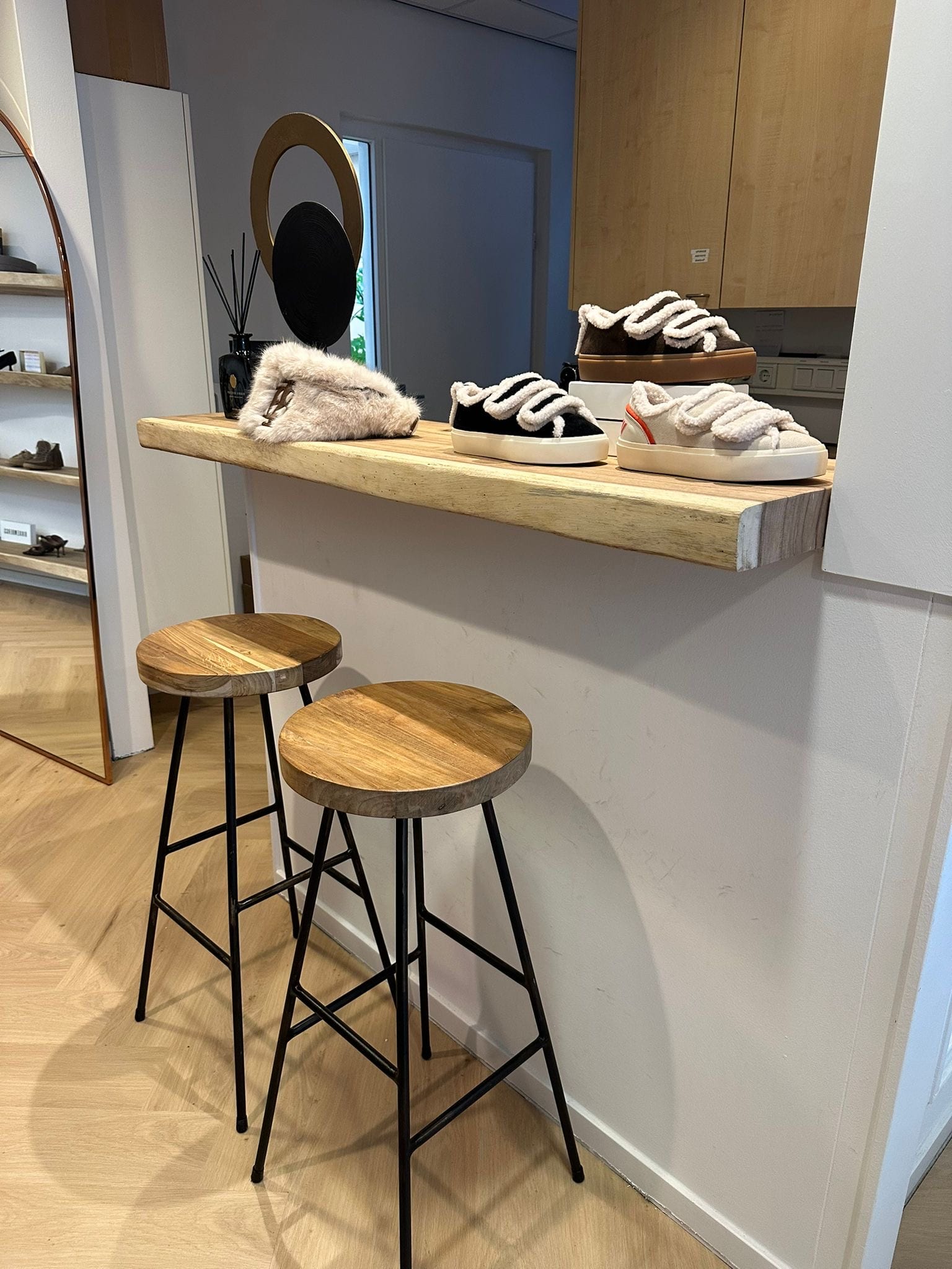 Barhocker mit Suar-Sitz an einer Suar-Bohle im Schuhgeschäft