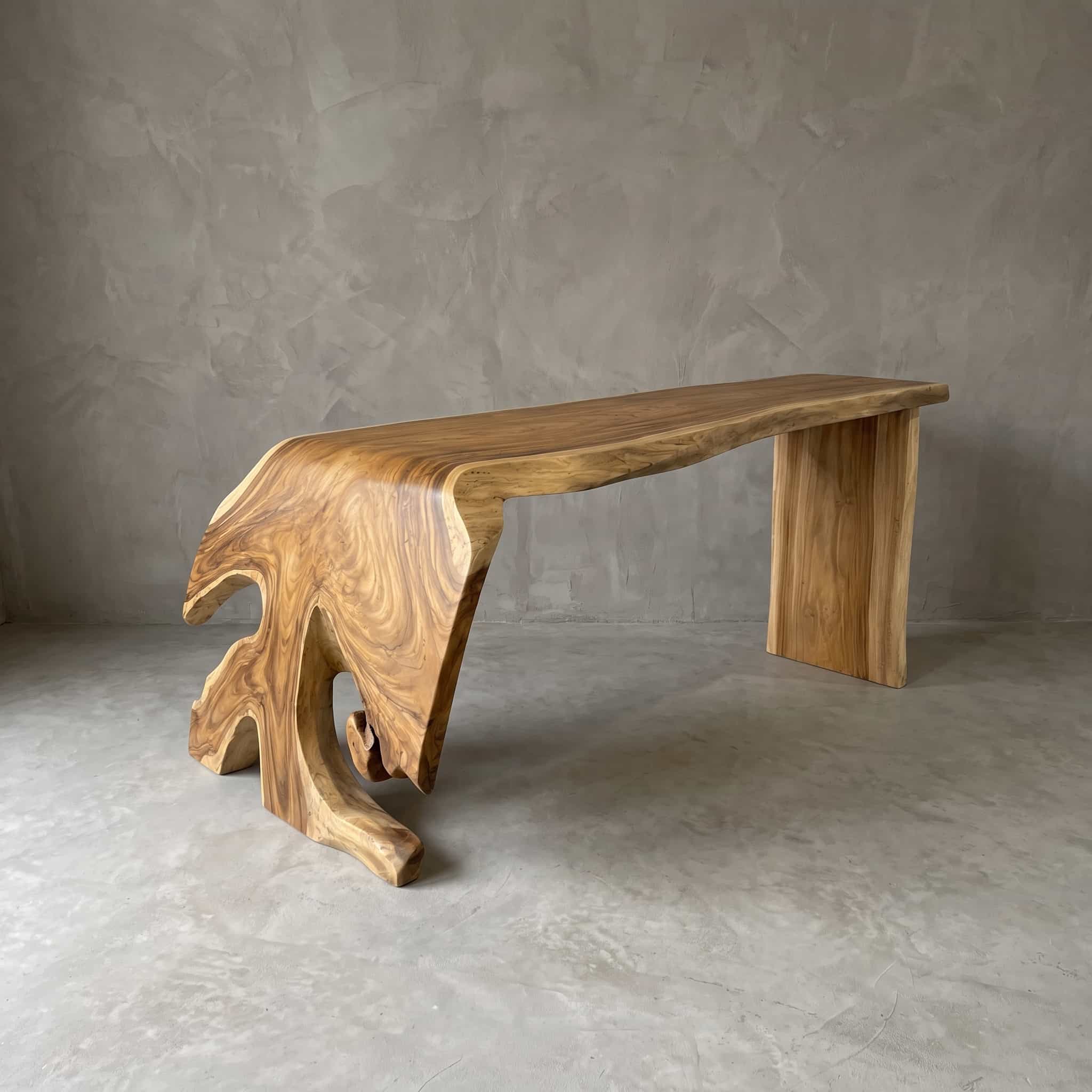 Suar wood bar table, river, an example at an angle from the front, with the top curving down in a wave on the left and a straight right leg
