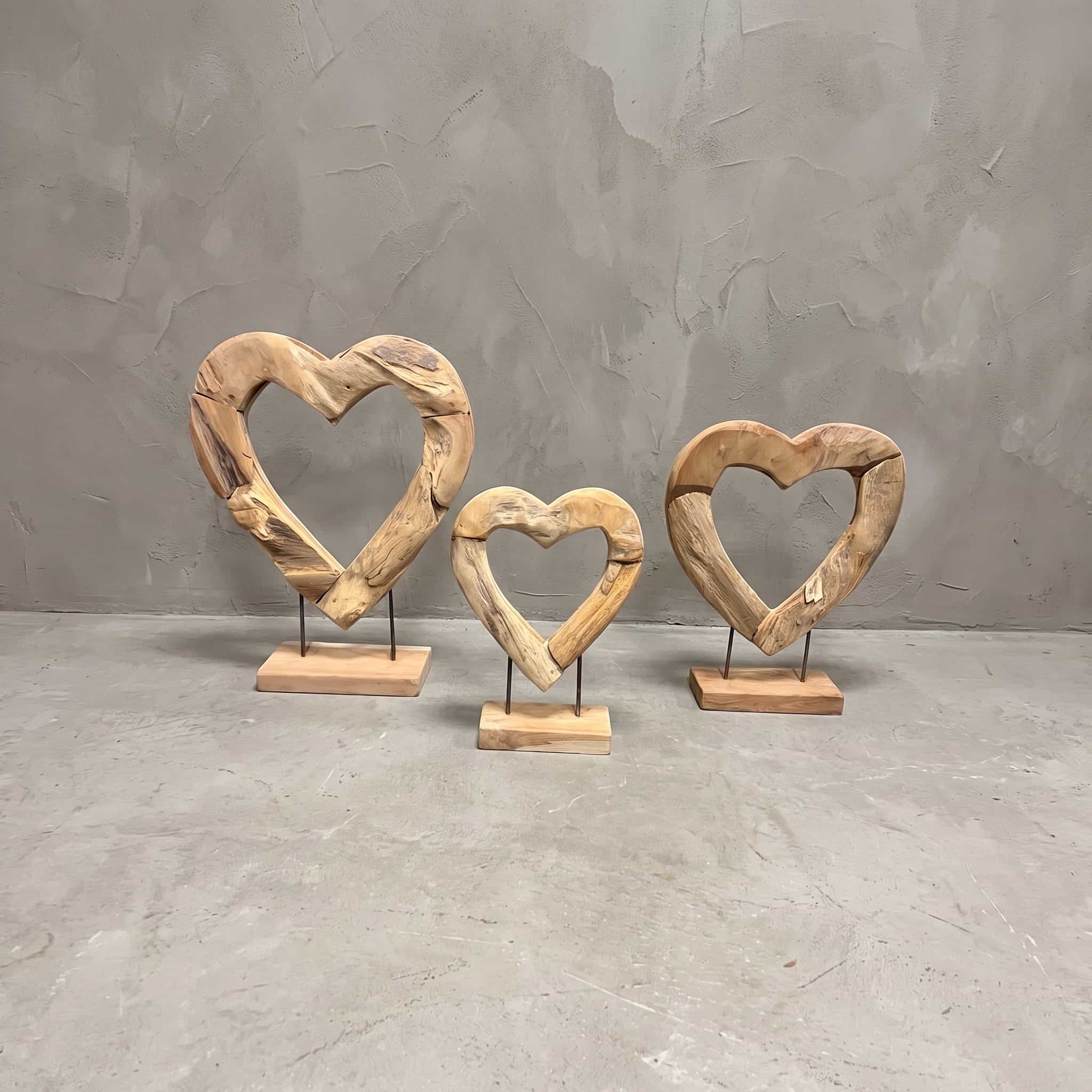 Sokkels van gerecycled teak, open hart, vooraanzicht van de open harten op twee staven in oplopende maten, voor een grijze wand