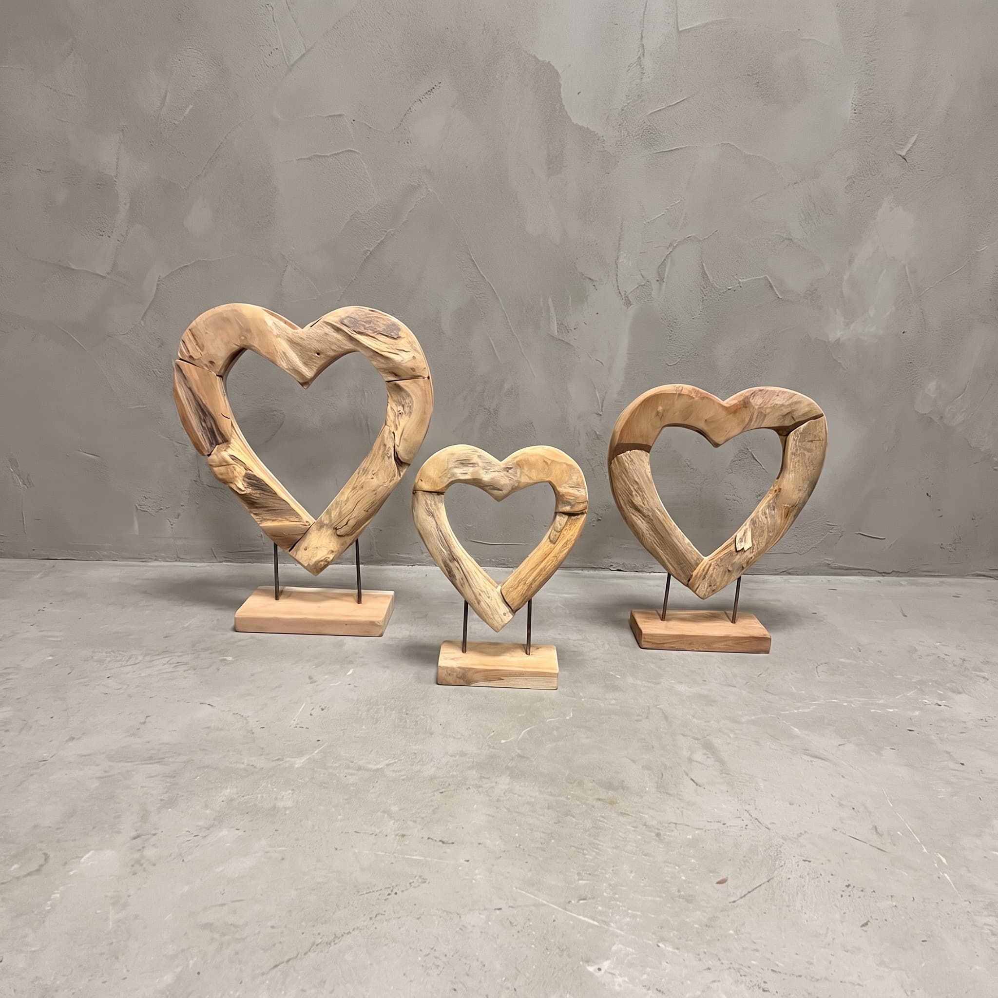Sokkels van gerecycled teak, open hart, vooraanzicht van de open harten op twee staven in oplopende maten, voor een grijze wand