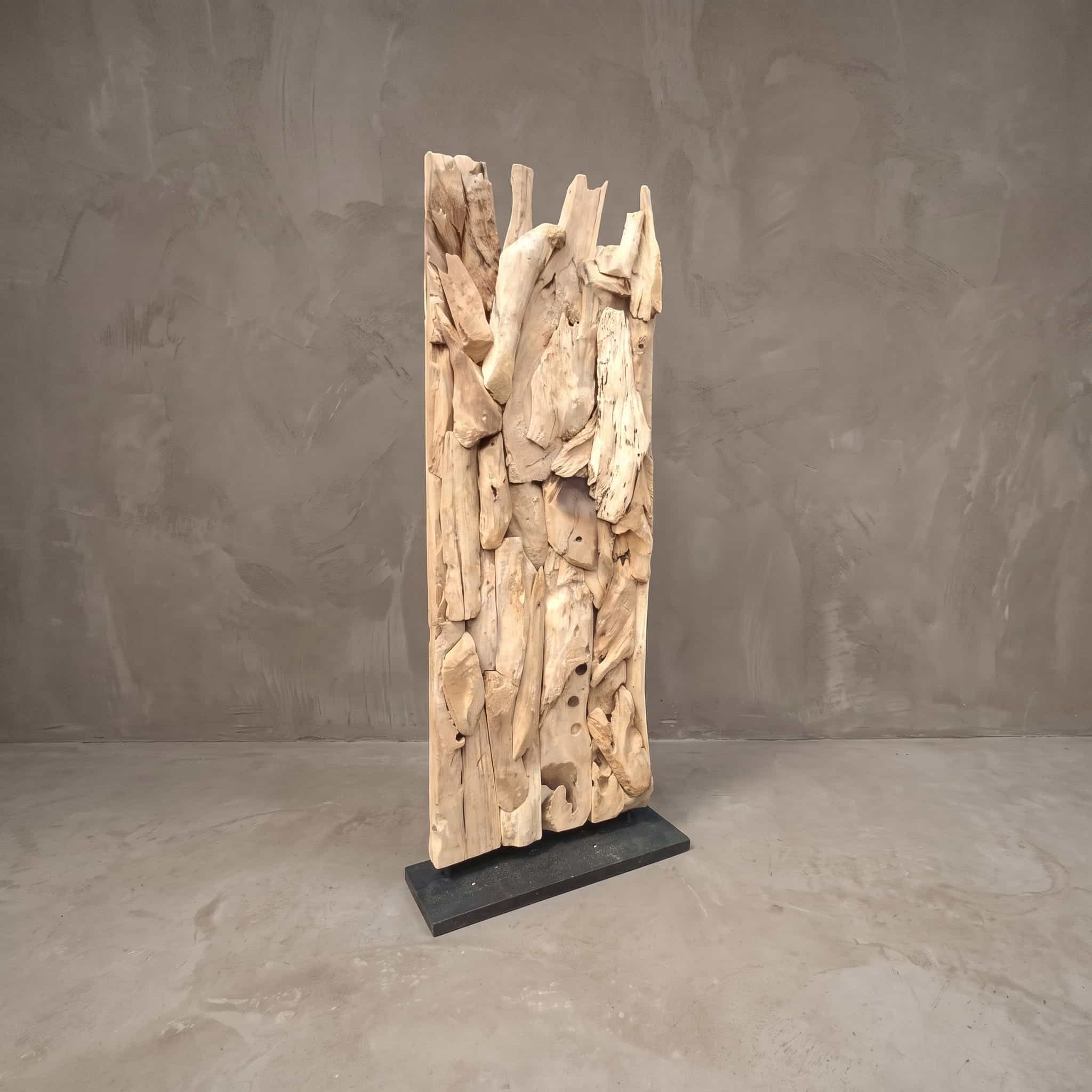 Roomdivider Rama van gerecycled teak, vooraanzicht van de stukken hout op de donkere voet, voor een grijze wand