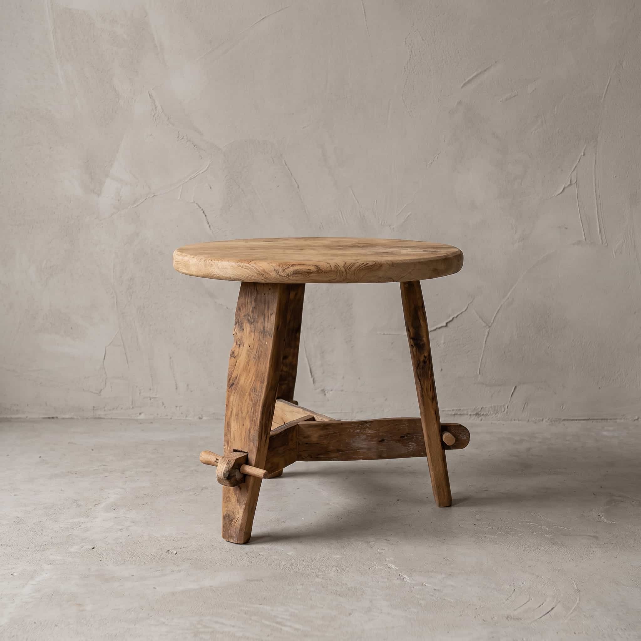 Salontafel Beben van teak, vooraanzicht van het ronde blad op drie schuine poten met dwarsbalken onderaan