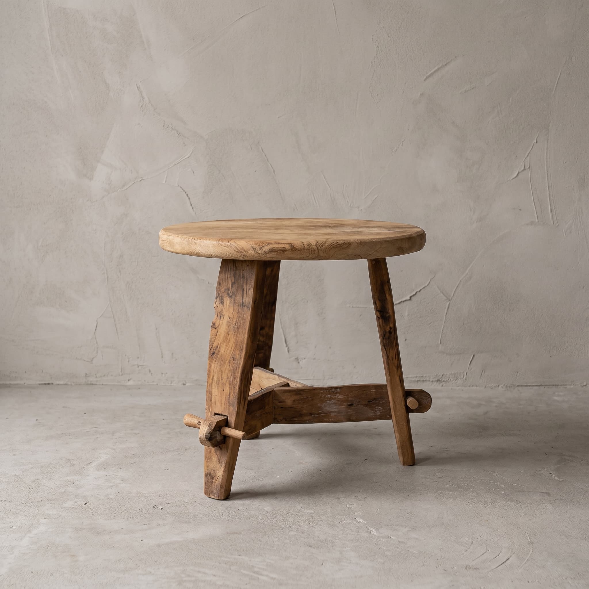 Salontafel Beben van teak, vooraanzicht van het ronde blad op drie schuine poten met dwarsbalken onderaan