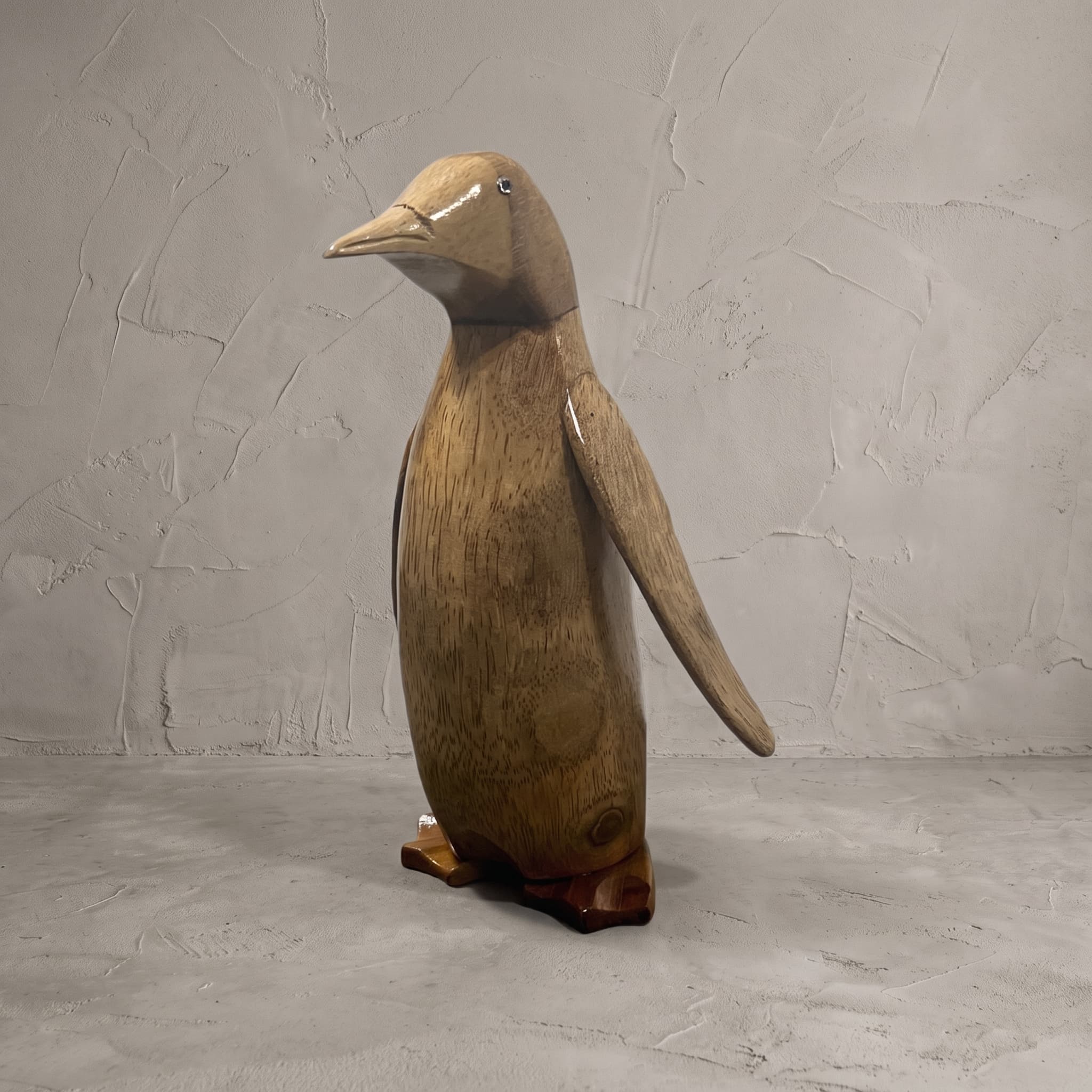 Pinguïn van bamboe, schuin vooraanzicht van de rechtopstaande pinguïn op roodbruine voeten voor een grijze wand