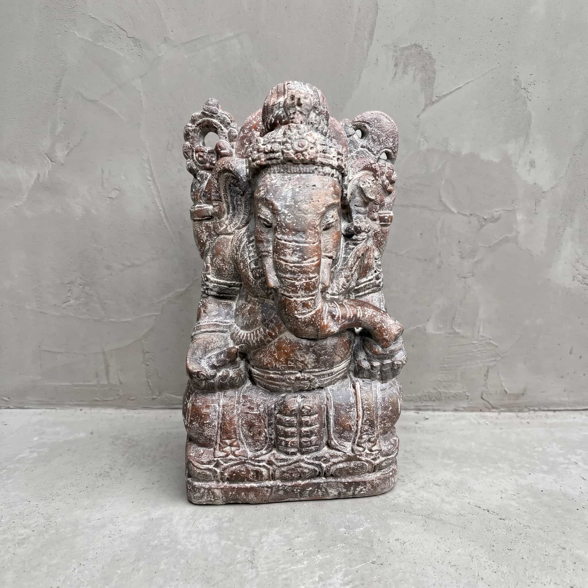 Beeld Ganesha van polystone, vooraanzicht van de zittende Ganesha met kroon en gekrulde slurf voor een grijze wand
