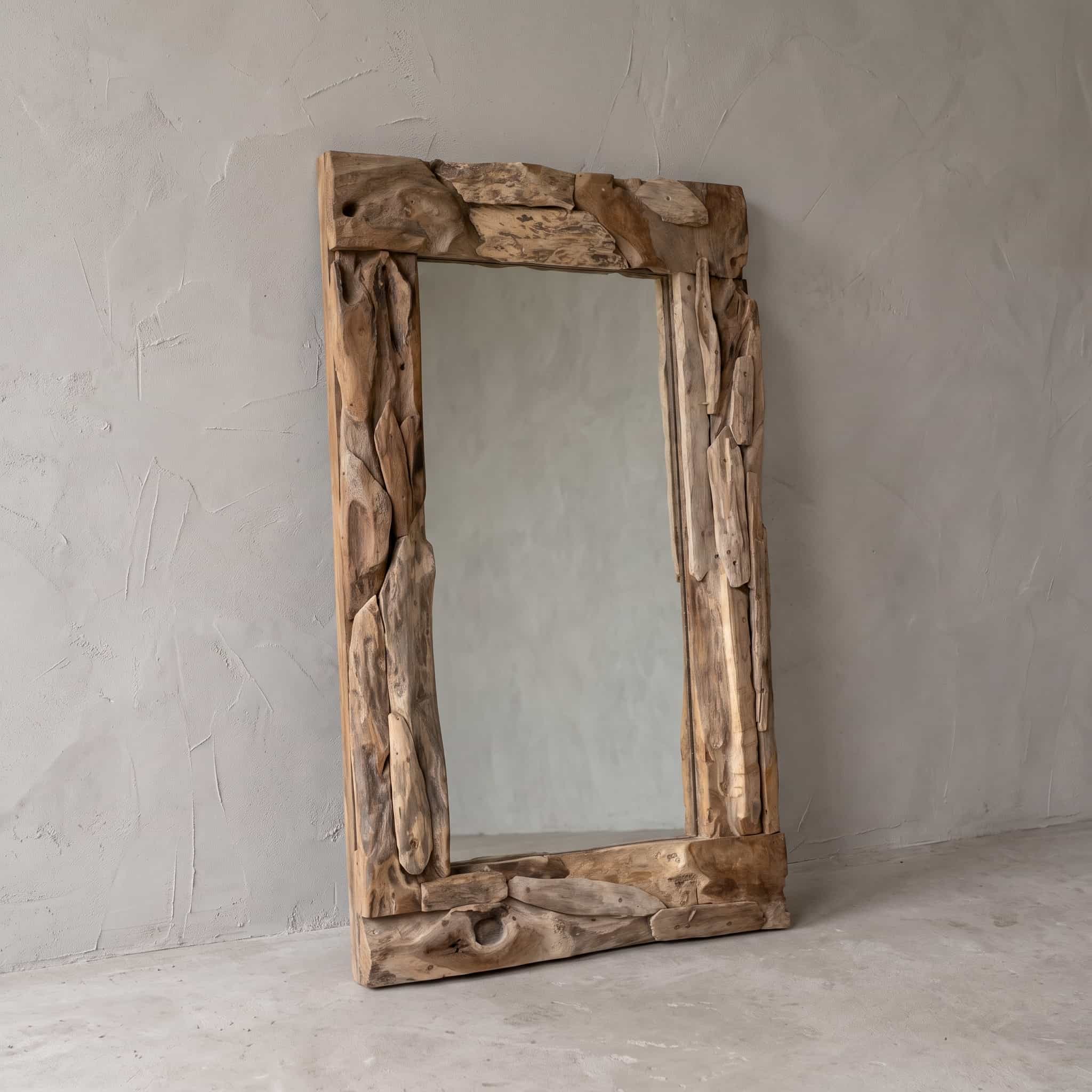 Spiegel Rama van teak, schuin vooraanzicht van de lijst van onregelmatige stukken hout tegen een grijze wand