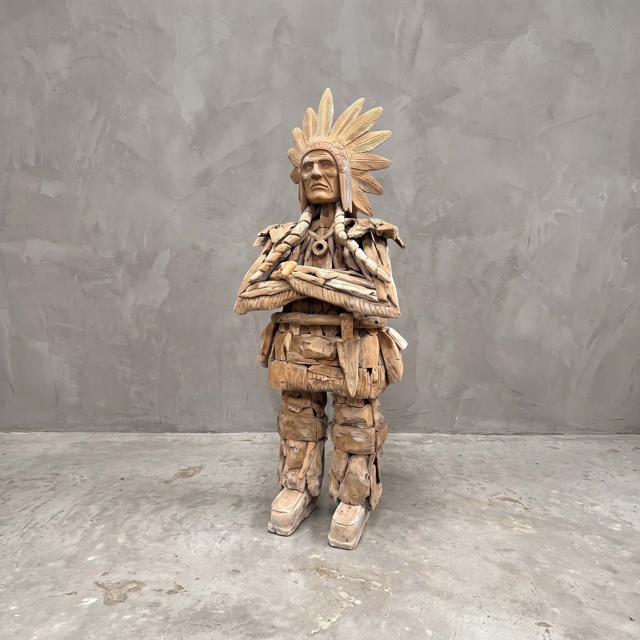 Indiaan van gerecycled teak, vooraanzicht van de staande figuur met verentooi en gekruiste armen voor een grijze wand