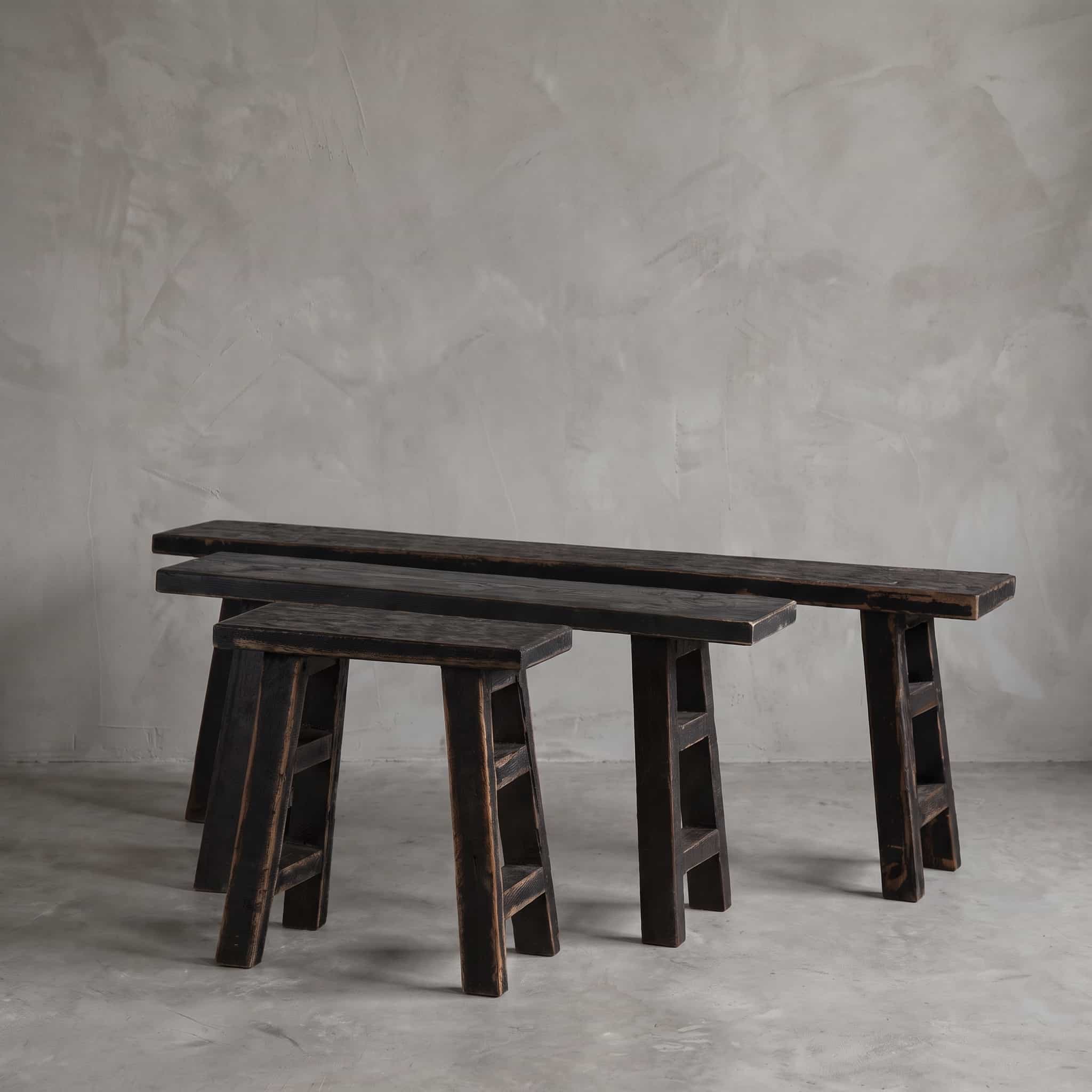 Bank School van gerecycled teak, Black Wash, banken in verschillende lengtes naast elkaar tegen een grijze wand