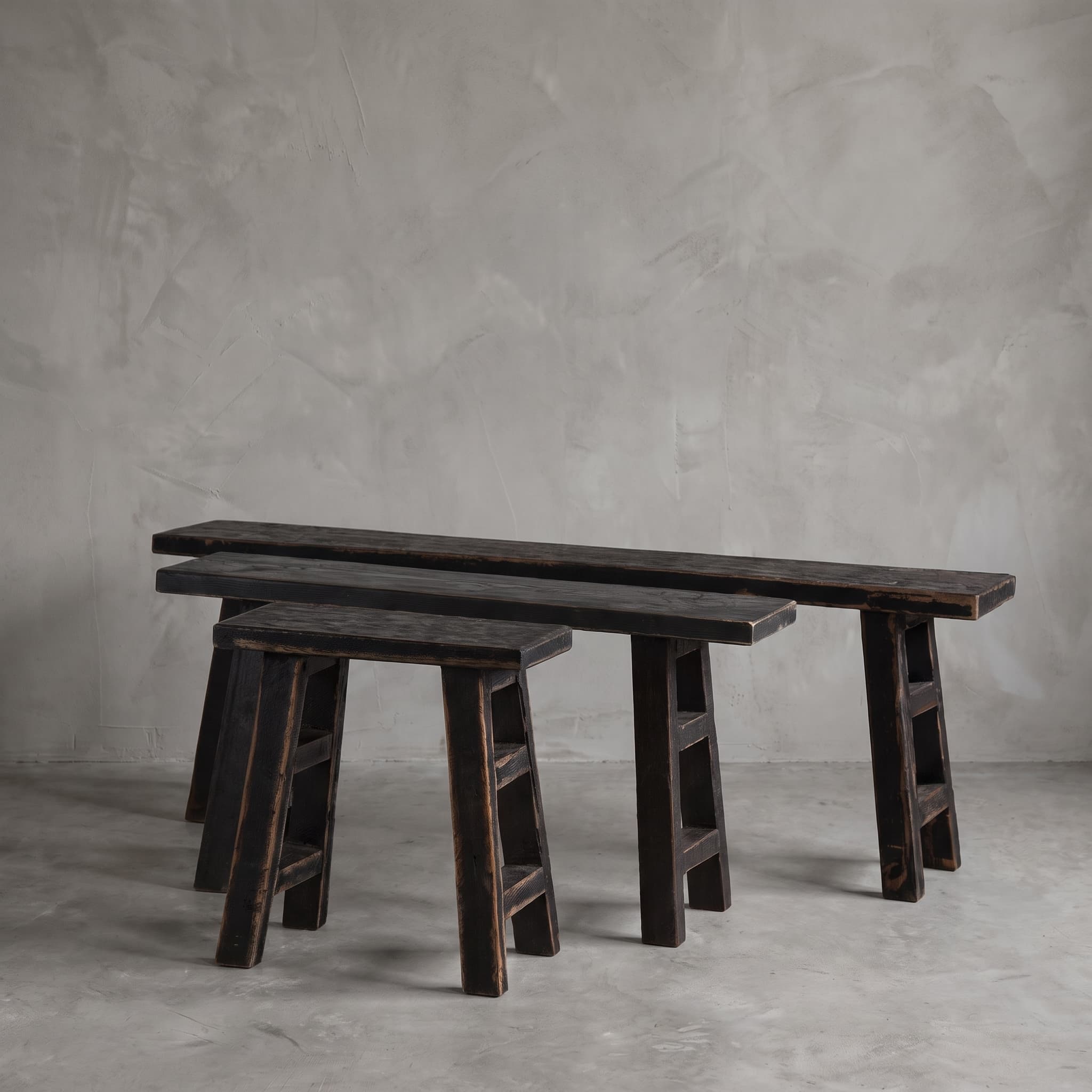 Bank School van gerecycled teak, Black Wash, banken in verschillende lengtes naast elkaar tegen een grijze wand