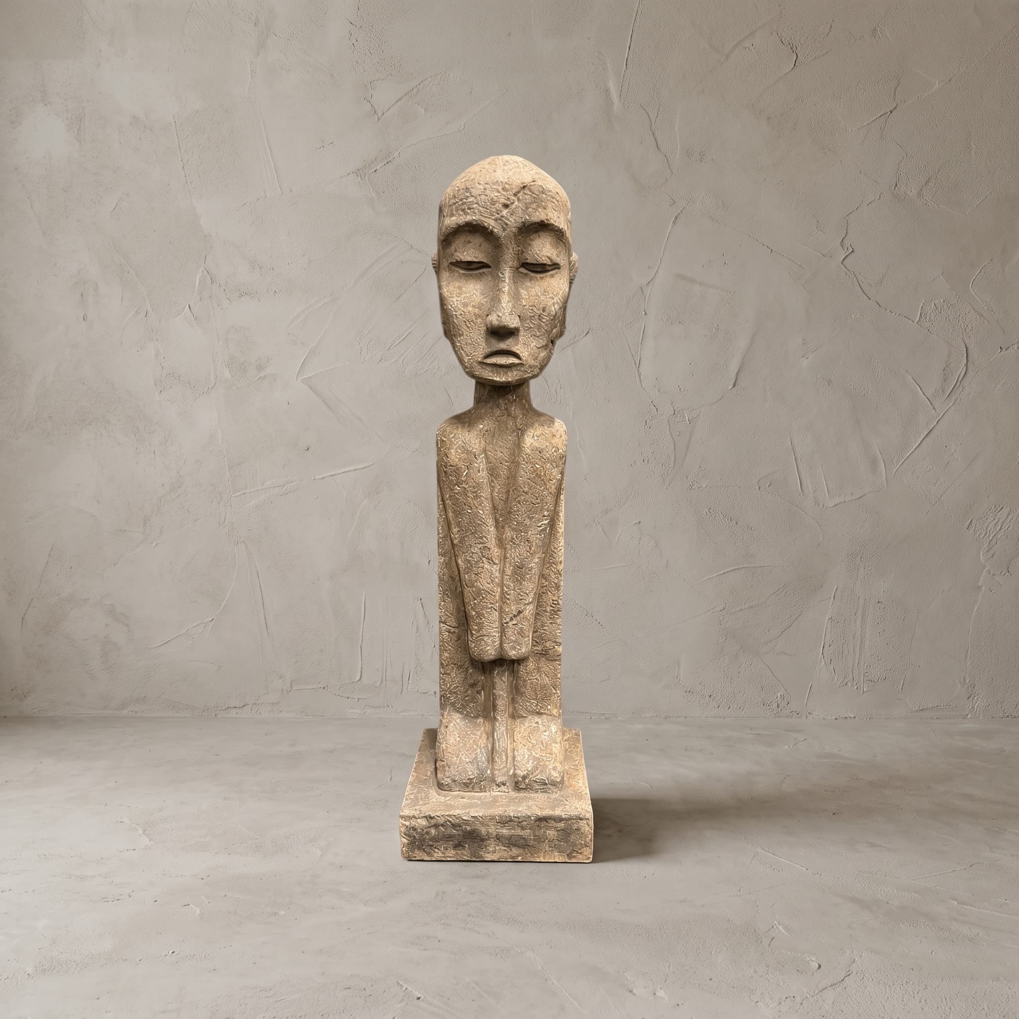 Beeld Konggo 2 van polystone, zandkleurig, vooraanzicht van de figuur met kaal hoofd en dunne hals voor een grijze wand