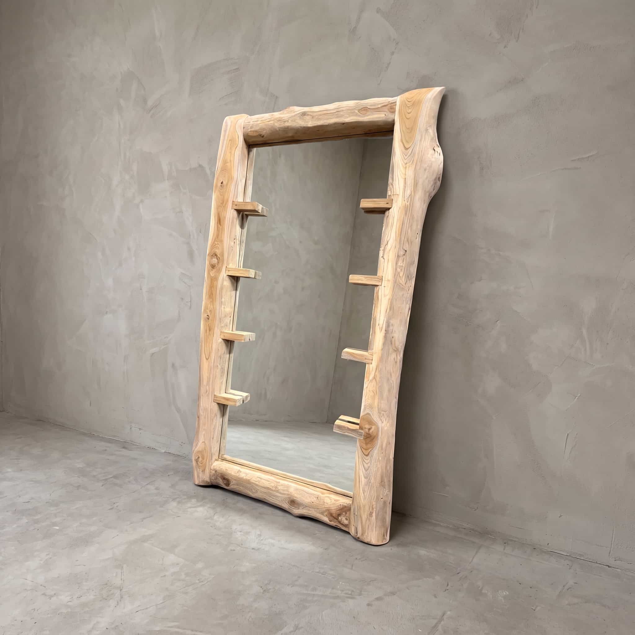 Boomspiegel Gito van teak, schuin vooraanzicht van de lijst met korte, platte blokjes aan beide zijden tegen een grijze wand