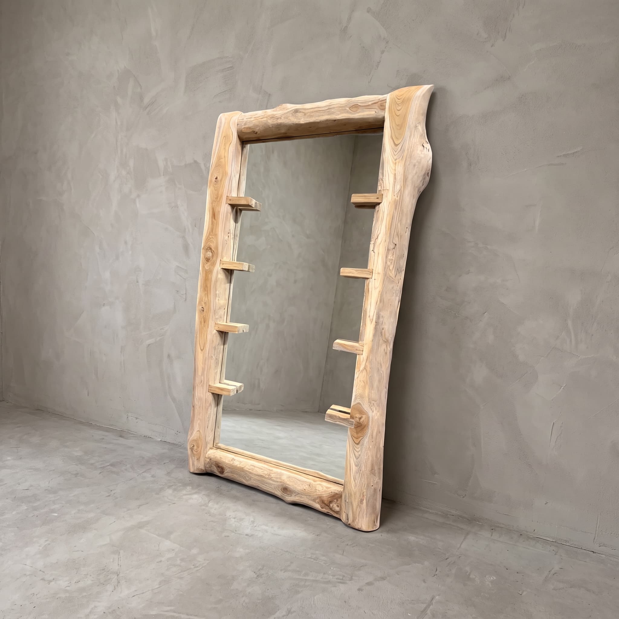 Boomspiegel Gito van teak, schuin vooraanzicht van de lijst met korte, platte blokjes aan beide zijden tegen een grijze wand