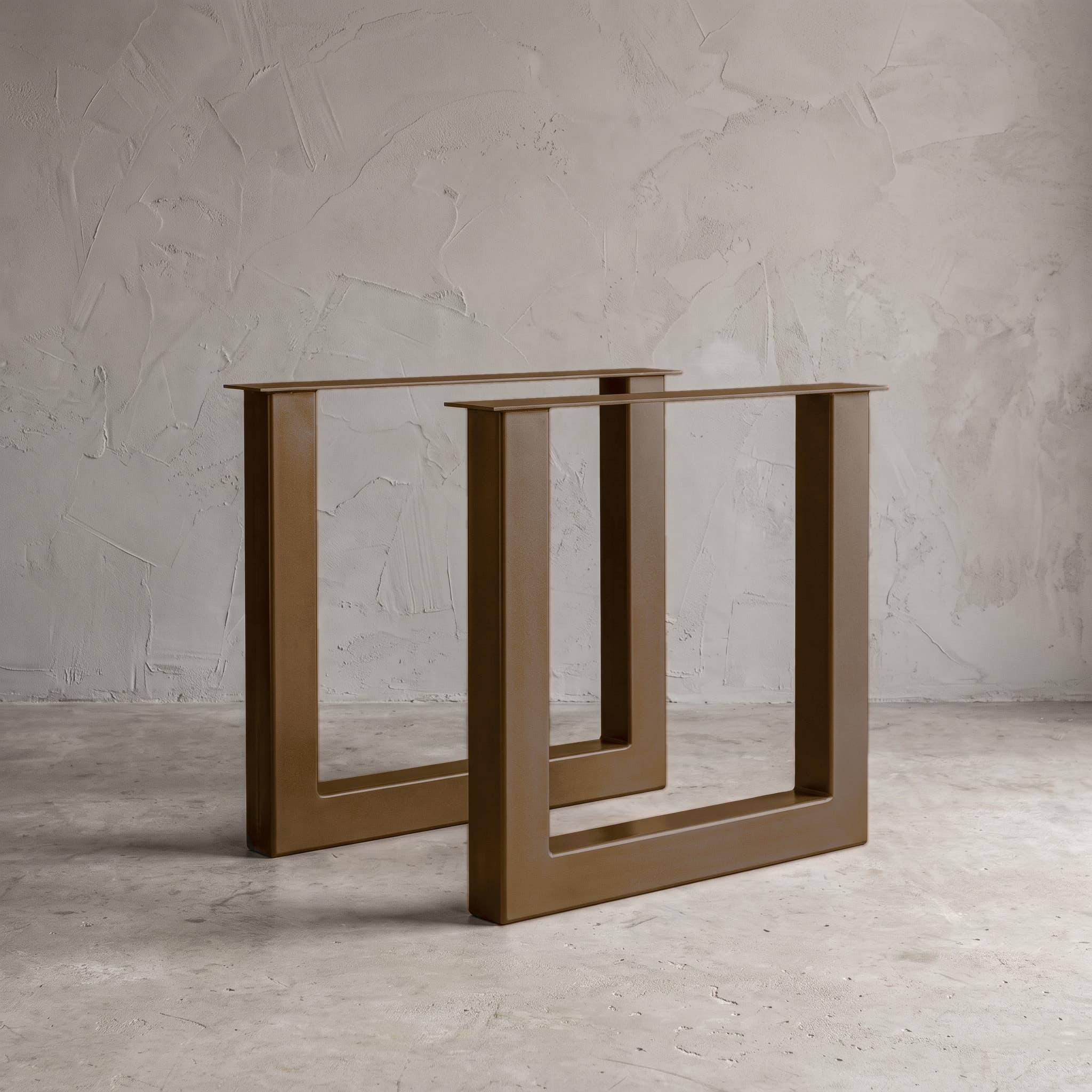 Onderstel U van metaal, gepoedercoat stalen tafelonderstel in Smoked Brown, met een tweede frame erachter tegen een grijze wand