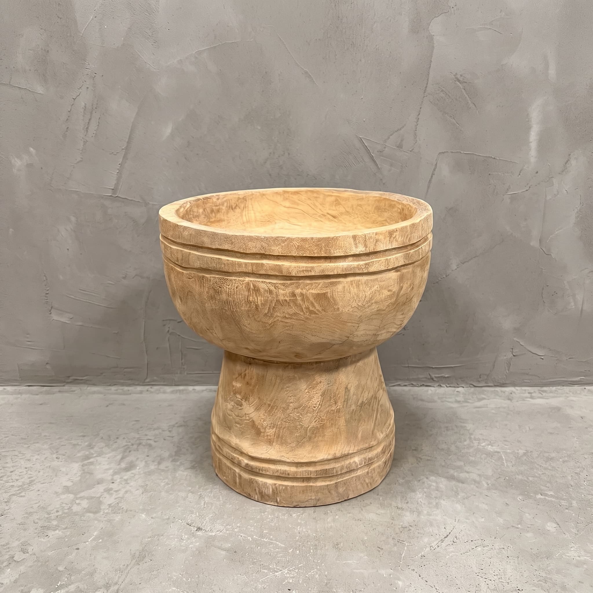 Pot Roots Ray van gerecycled teak, vooraanzicht van de ronde kom op een voet tegen een grijze wand
