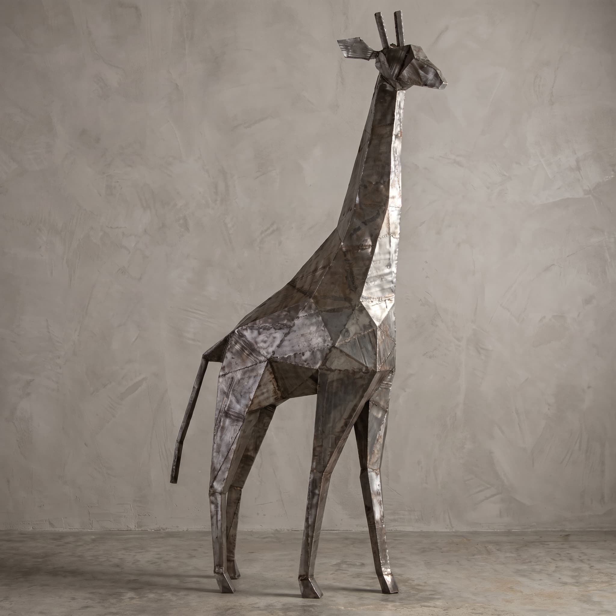 Giraf van metaal, zijaanzicht van de hoekige figuur met lange hals voor een lichte wand
