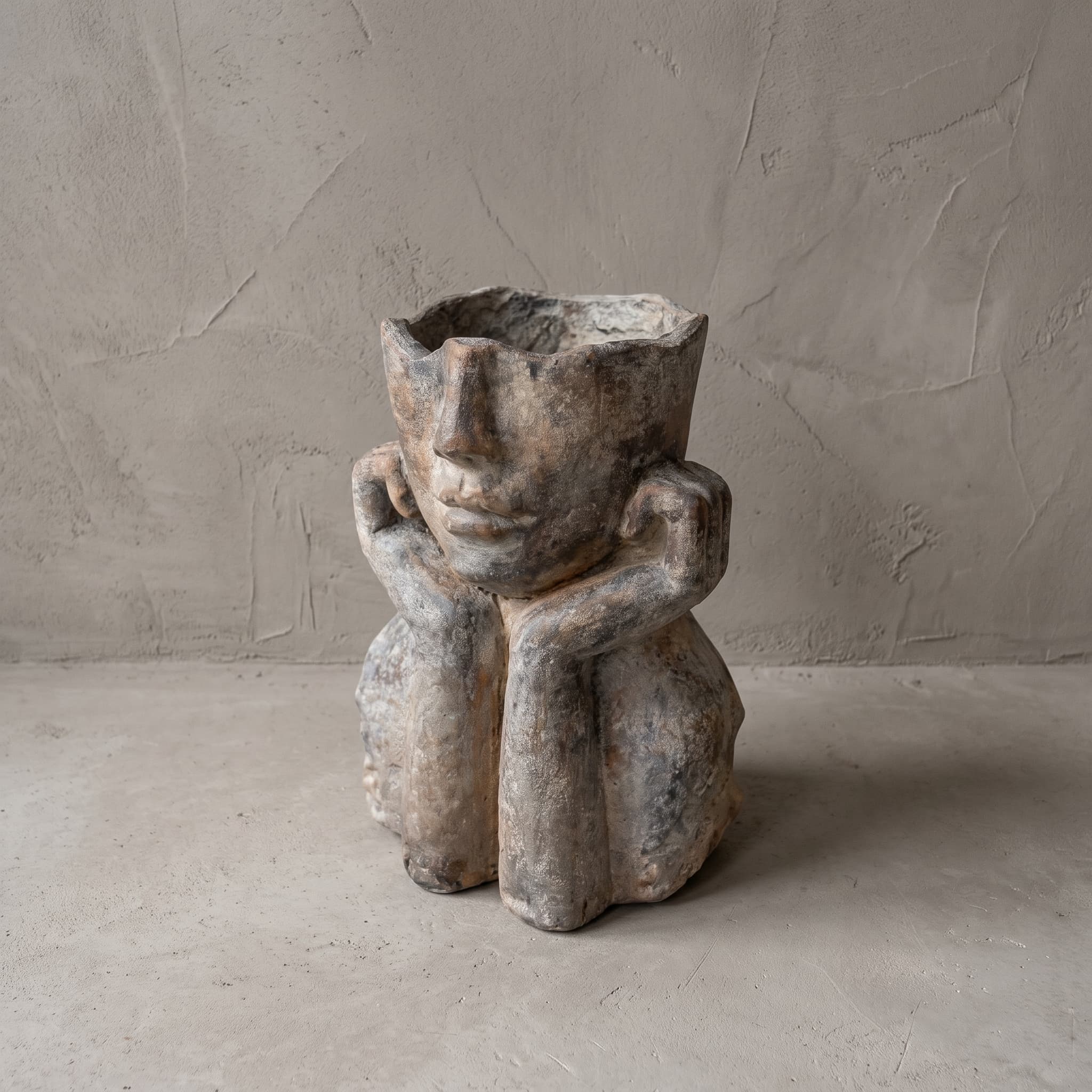 Pot van polystone, zittende figuur, vooraanzicht met het gezicht in beide handen en de opening boven de neus