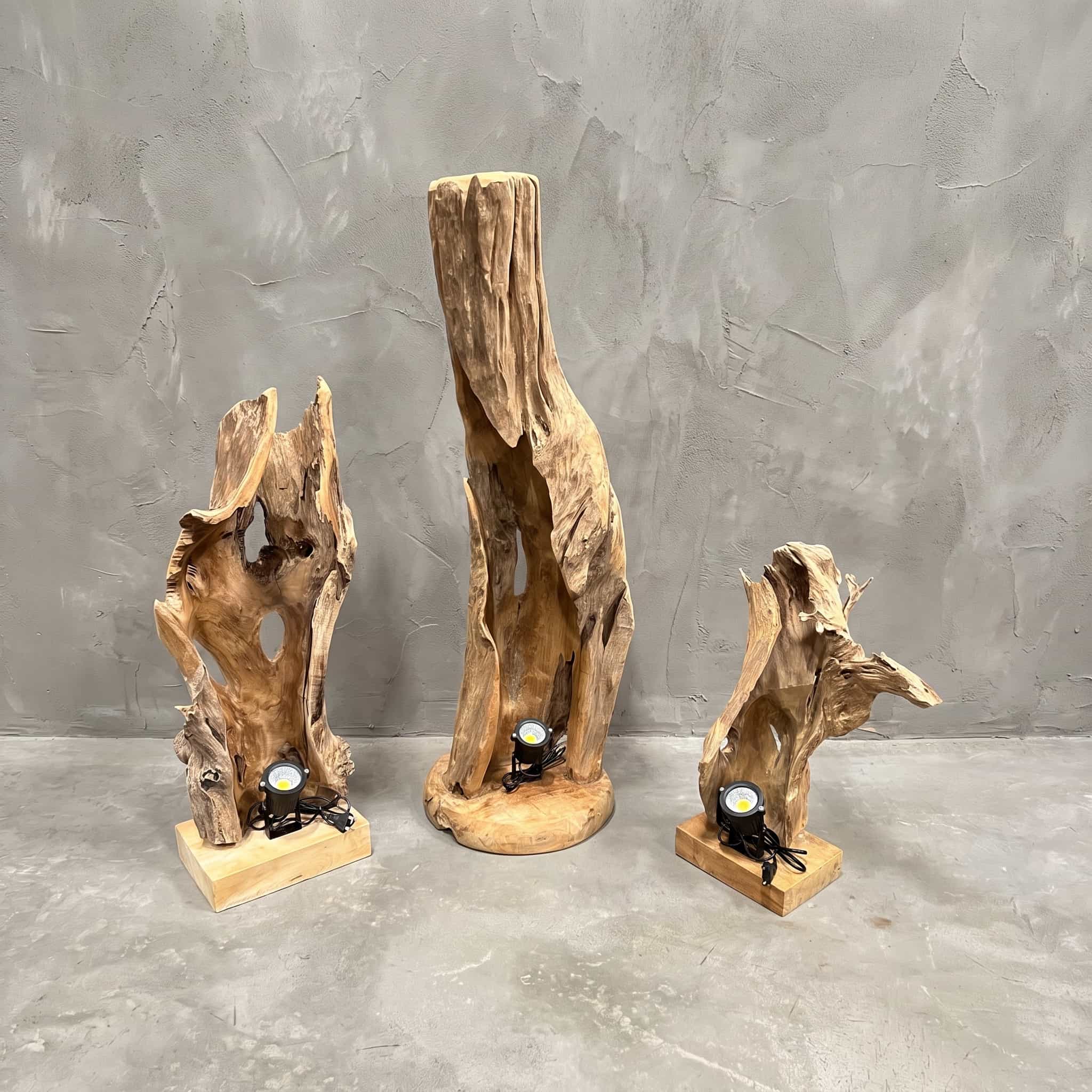 Lamp Nurali van teak, lampen uit de serie naast elkaar, elk een open, grillig stuk hout rechtop op een voet