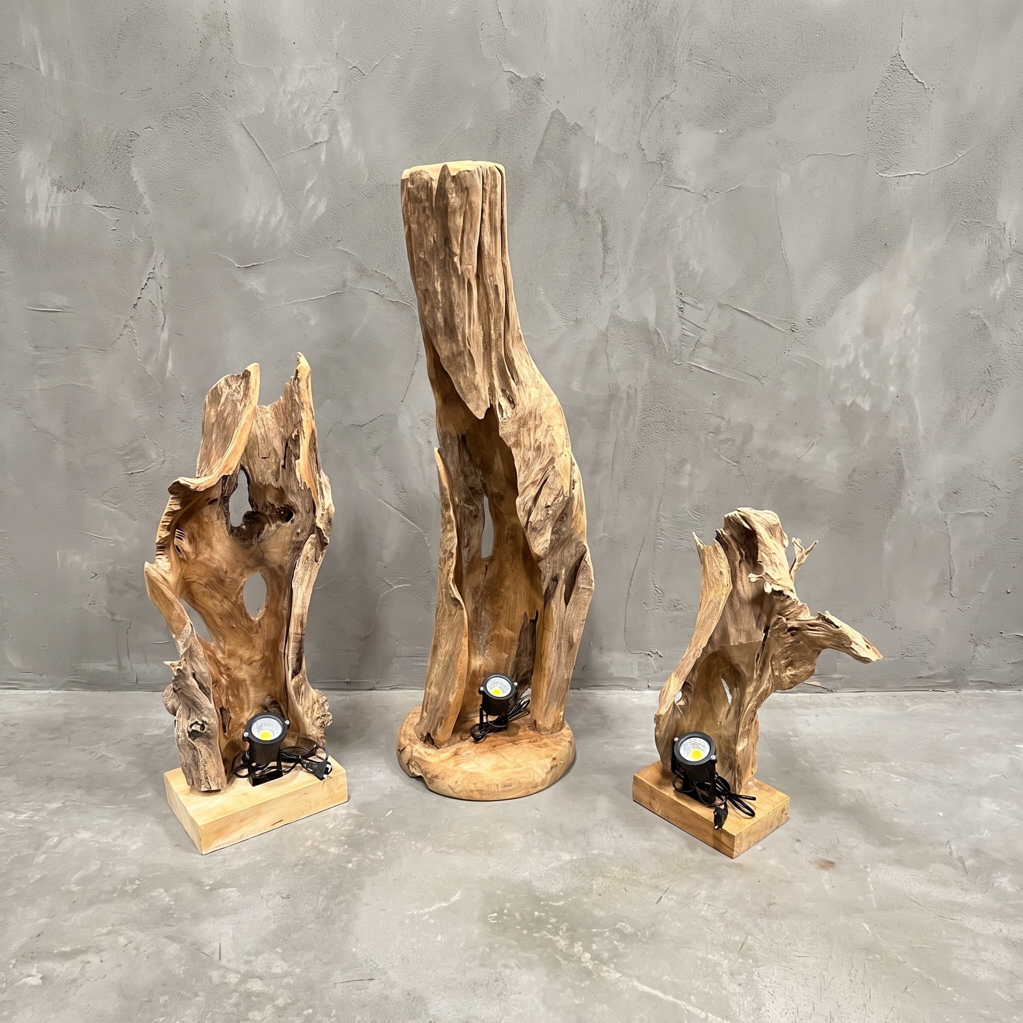 Lamp Nurali van teak, lampen uit de serie naast elkaar, elk een open, grillig stuk hout rechtop op een voet