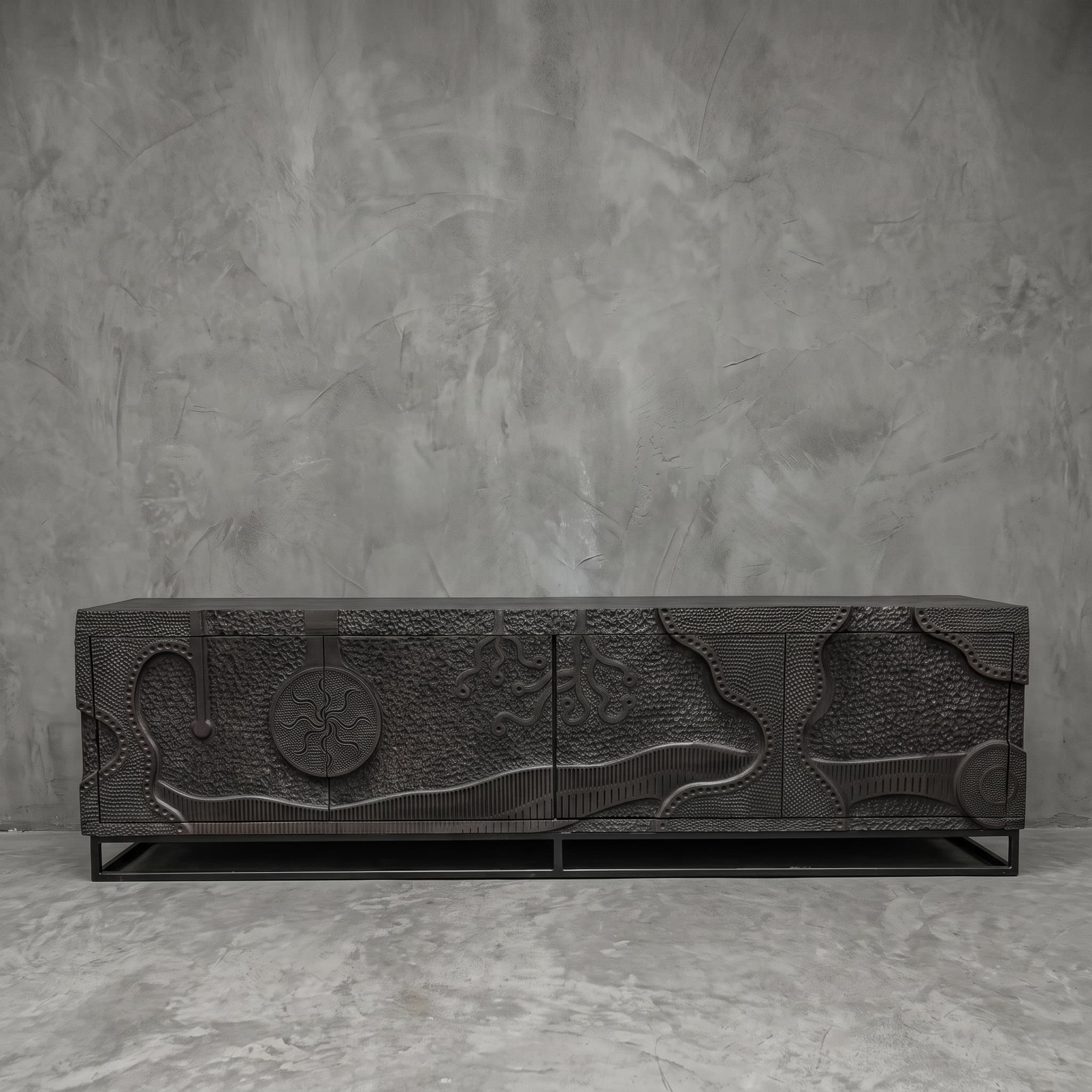 Ukiran teak TV unit seen straight from the front, with wavy bands and branching forms in anthracite above a low, open base