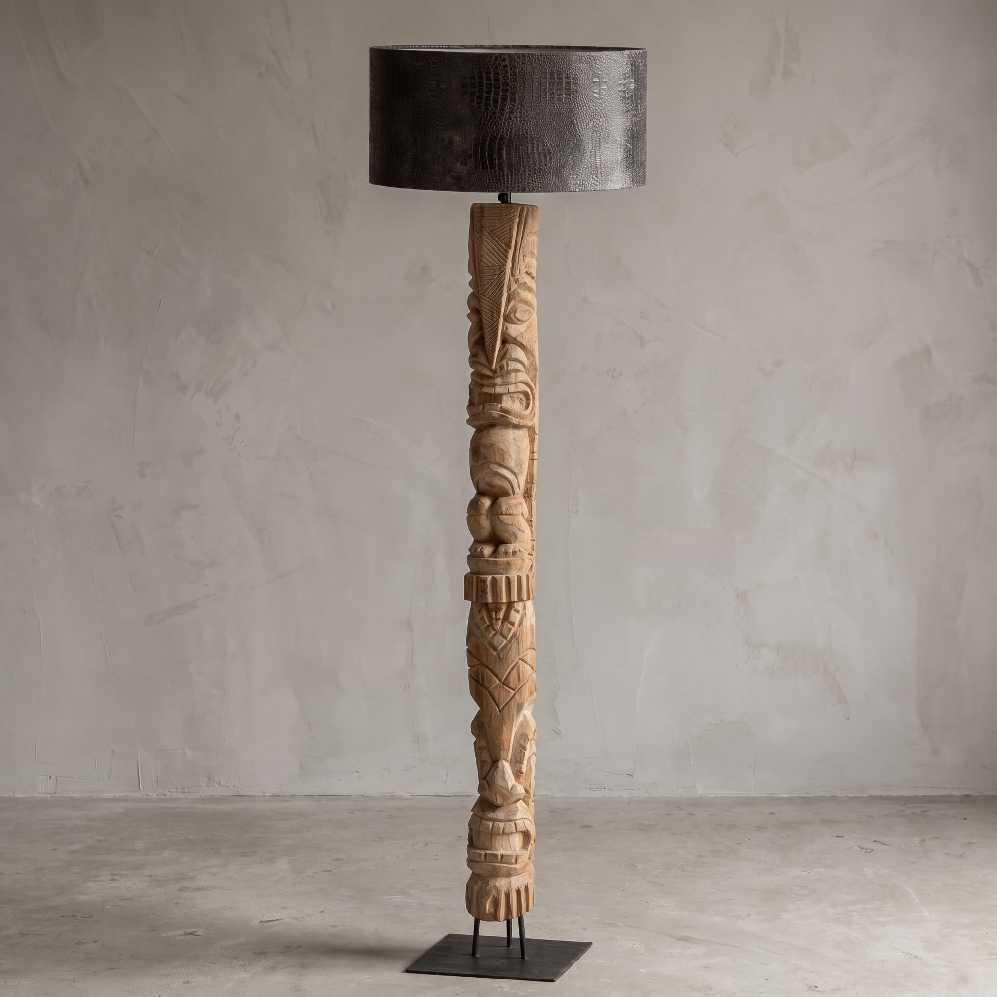 Lamp van teak en metaal, totemvorm, vooraanzicht van de lichte totem met figuren in reliëf op een vierkante voetplaat