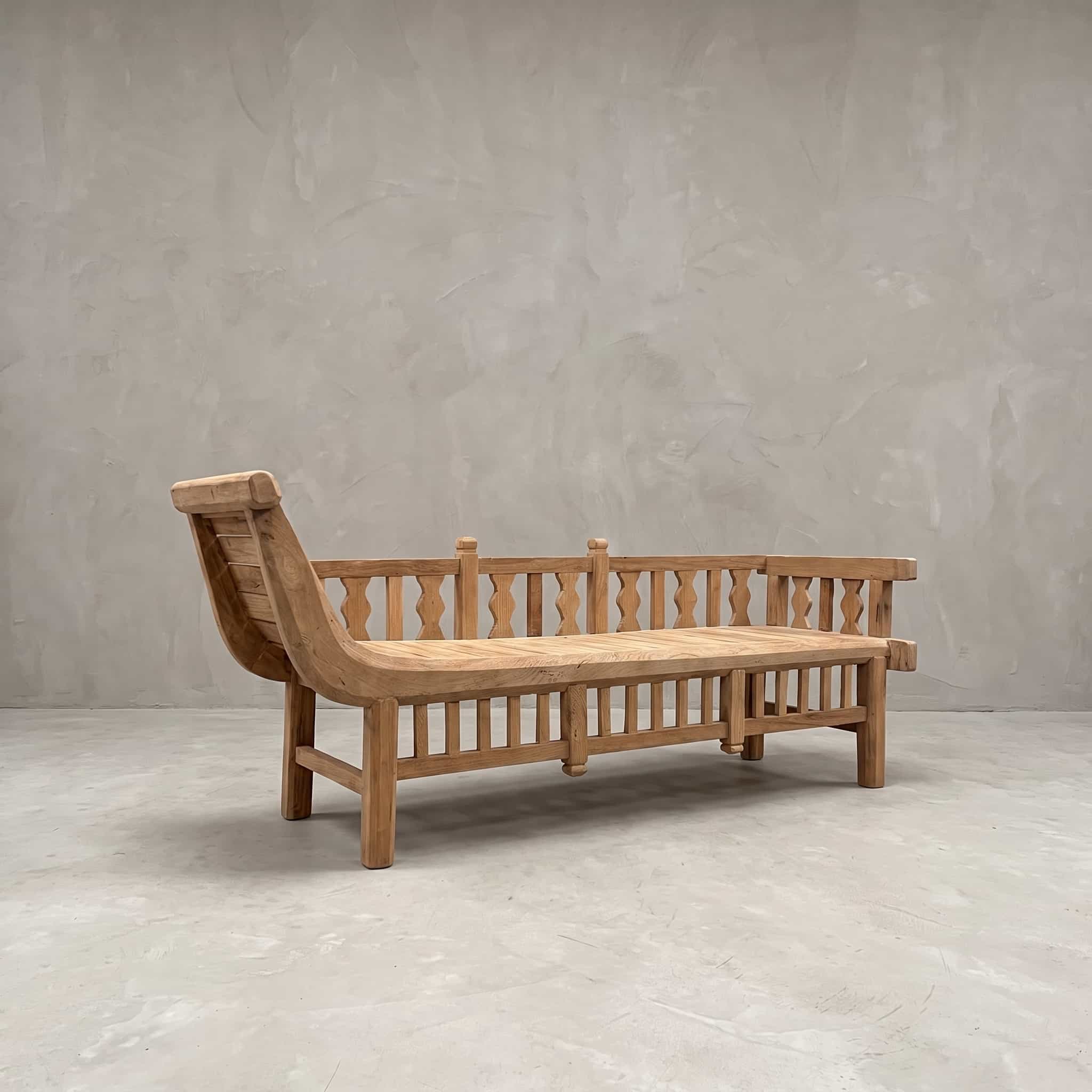 Bank Java Daydream van teak, schuin vooraanzicht met het gebogen hoofdeinde en de rugleuning met balusters