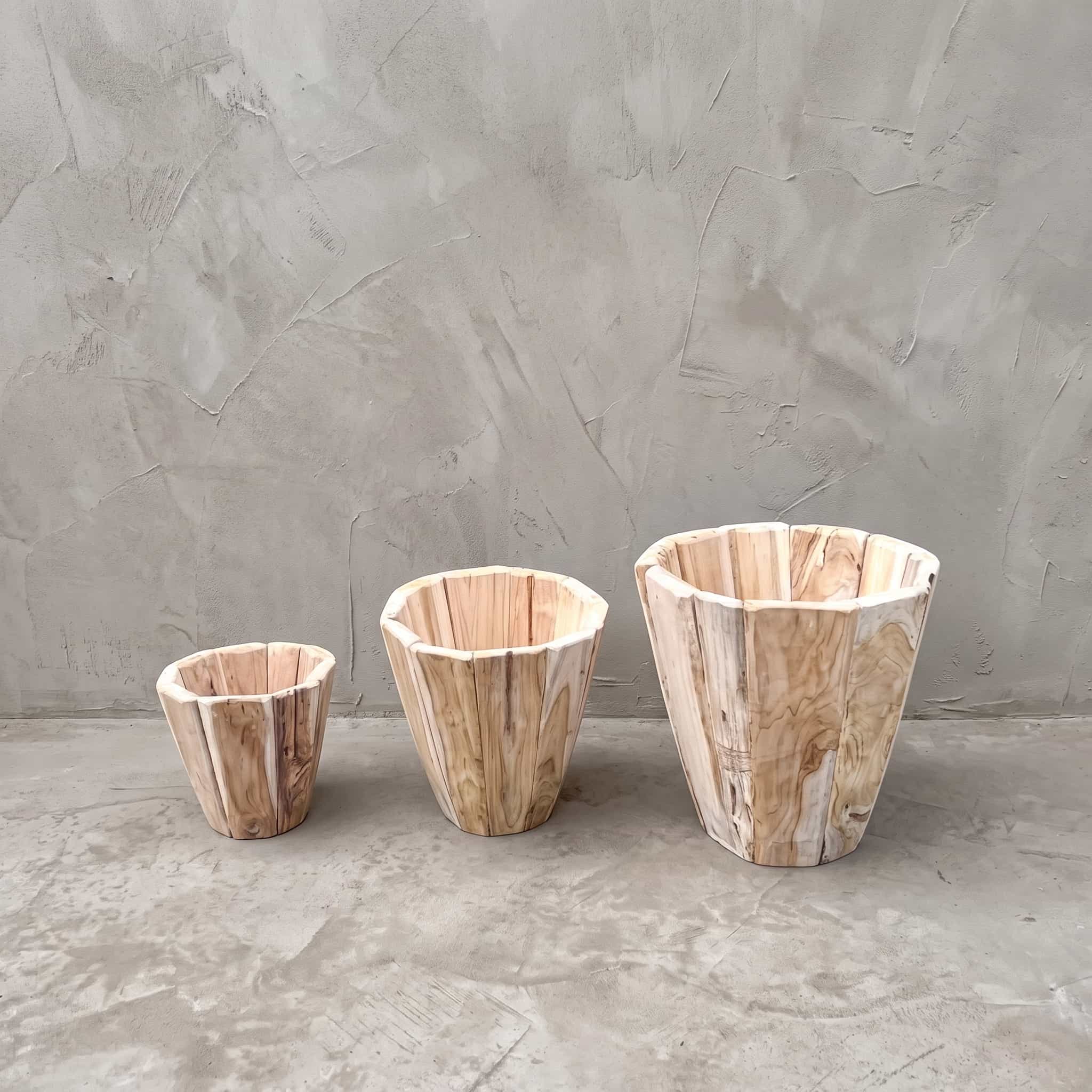 Pot Jono van gerecycled teak, set van 3, de drie veelhoekige potten naast elkaar op een betonvloer