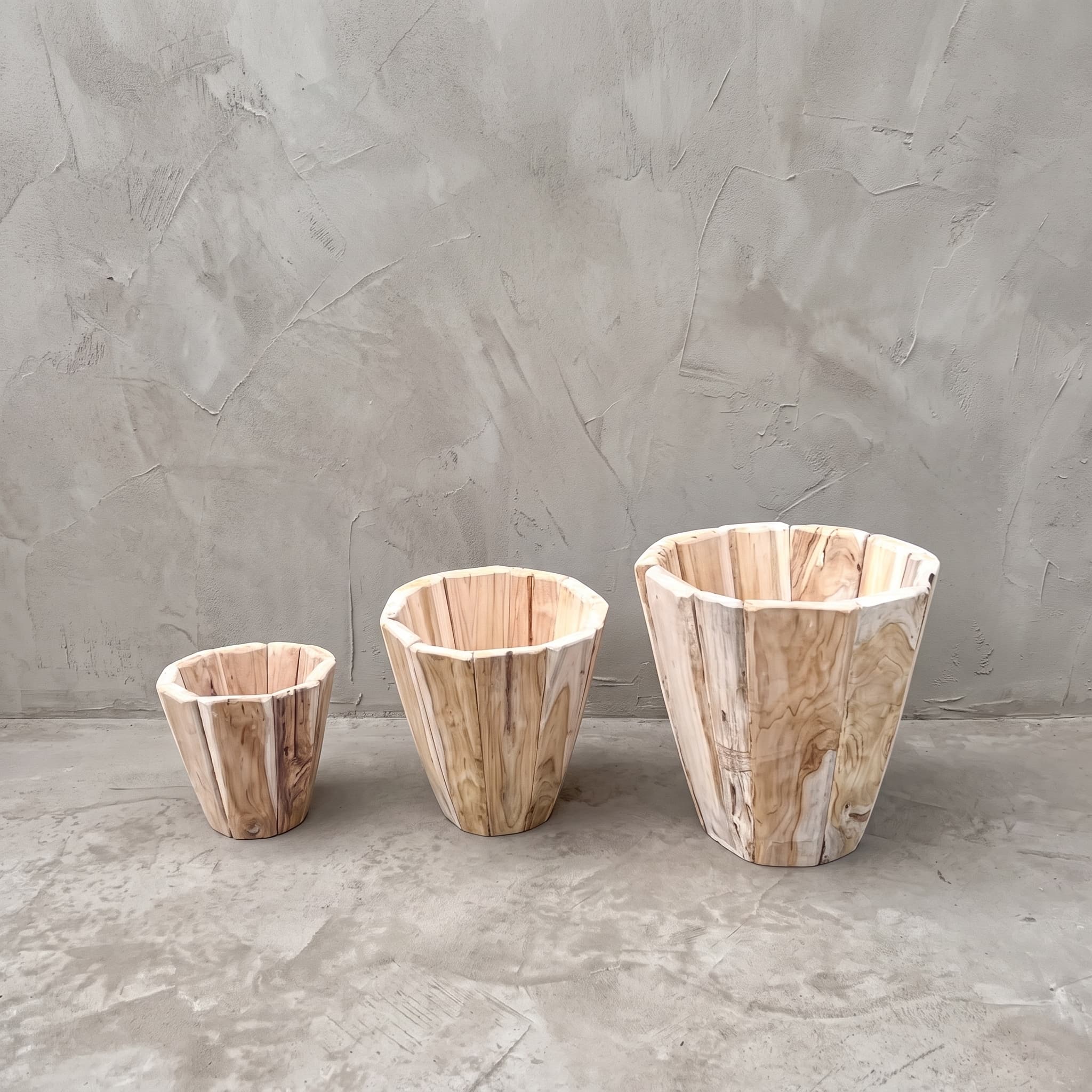 Pot Jono van gerecycled teak, set van 3, de drie veelhoekige potten naast elkaar op een betonvloer