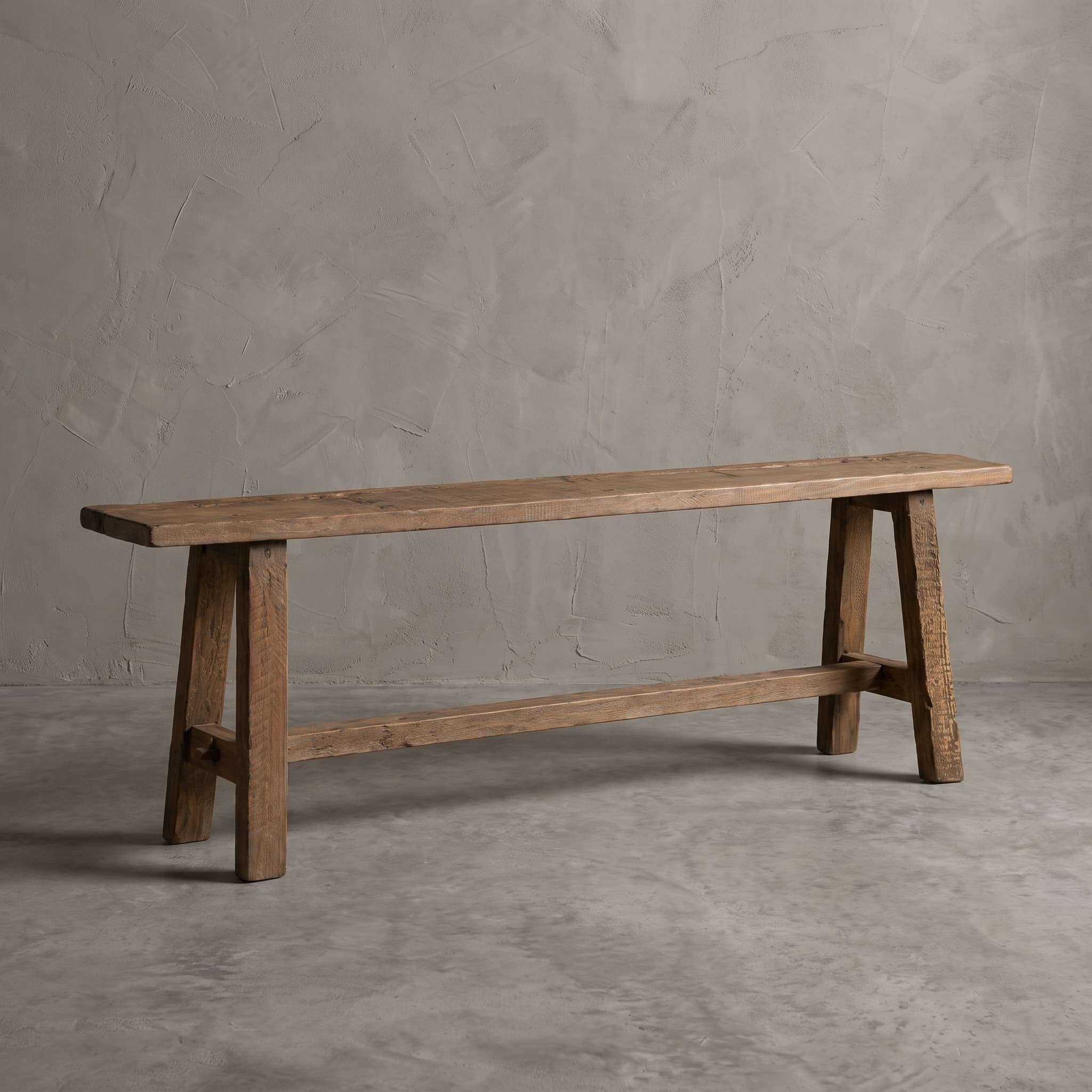 Bank School van gerecycled teak, vooraanzicht van het lange verweerde blad op schuine poten met een lage verbindingslat