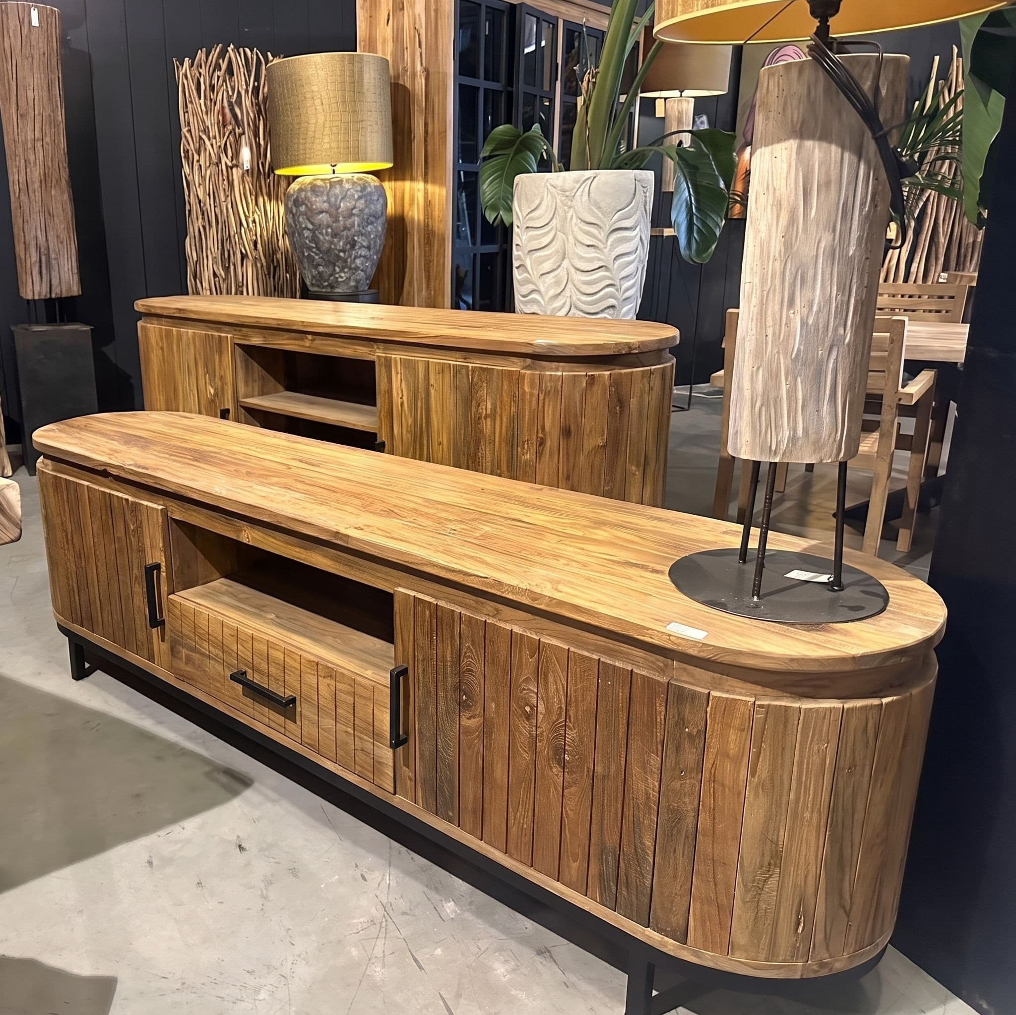 Dressoir Kira van gerecycled teak en metaal, twee meubels uit de collectie in de showroom, met ronde zijkanten van verticale latten